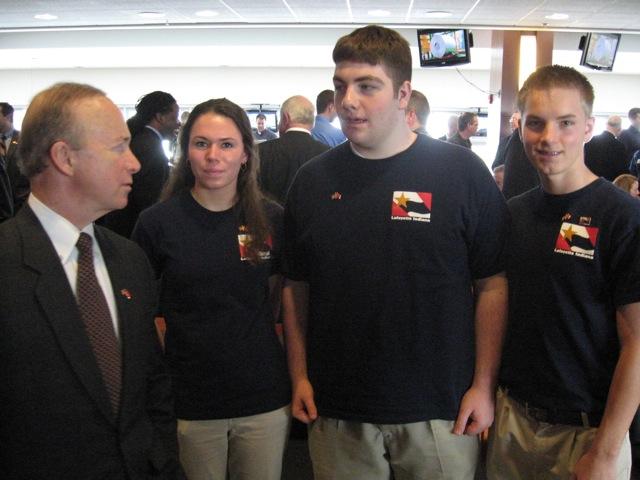 3 teens and a man in a suit talking